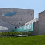 The exterior, sidewalk, and front yard of the Walker Art Center with a large frosted glass sign reading 