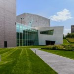 The back of the Walker Art Center with a large grass yard and a art sculpture on a sunny day.