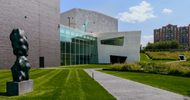 The back of the Walker Art Center with a large grass yard and a art sculpture on a sunny day.