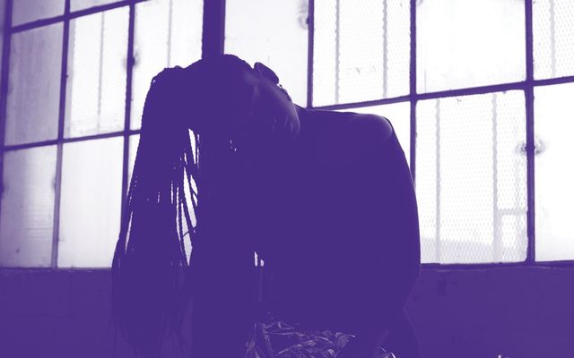 A purple and white photo of an adult silhouette with long braids in front of a brightly light window
