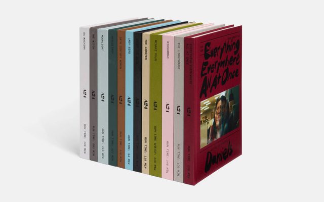A set of ten colorful film script books standing upright in a row on a white background.