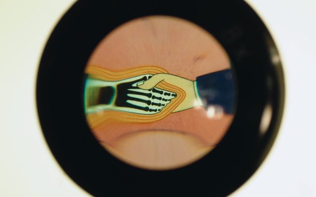 a thick black outlined circle with cartoon of a human hand shaking a black and white skeletal hand with orange outlines surrounding it and a strip of the same image repeating behind the circle