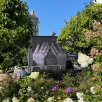 A garden with a food truck behind some trees with a mural of hands and eye.