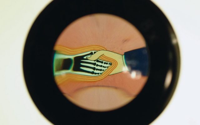 a thick black outlined circle with cartoon of a human hand shaking a black and white skeletal hand with orange outlines surrounding it