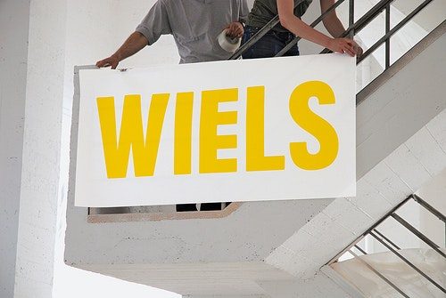 Two adults installing a white sign reading 