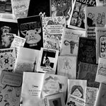 Black and white image of several zines laid out on a table.
