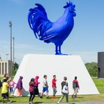 epp2018aucs0601msg_011 A group of adolescents walk past and outdoor art structure of a large blue rooster