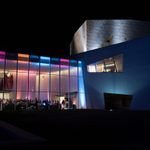 ex2015ipop_opn_102 The exterior of the Walker Art Center lit up and large windows revealing colorful lights and a crowd of people for a Walker Art Center event