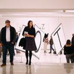 Several people walking around a large installation of giant letters spread throughout the space