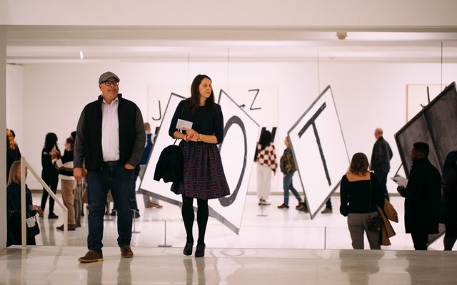 Several people walking around a large installation of giant letters spread throughout the space