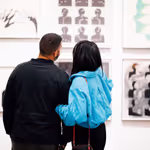 ex2023mr_opn_050 A couple linked in arms looking at artwork displayed on the wall