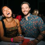 Two young adults posing for a photo, wearing event bracelets and holding a beverage, at a night event at the Walker Art Center