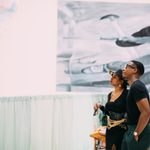 Two adults standing and looking up at an art piece hanging on the wall at a Walk Art Exhibit