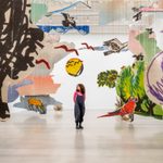 An adult standing in the middle of a large paper art installation