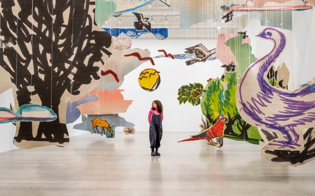 An adult standing in the middle of a large paper art installation