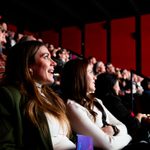 People sitting in the theatre audience looking towards a lit area