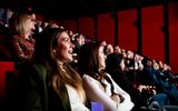 People sitting in the theatre audience looking towards a lit area