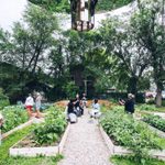 Adults and chidren explore an outdoors community garden art project during a sunny day.