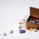 A small wooden box filled with small trinkets and some spread out on the table for display