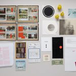 Spread out on display: historical images, printed material in red ink, tiny Spongebob smiley faces, a photo order envelope, a dollar bill, stickers, and envelopes